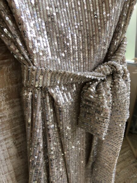 <p>Maxi vestido de lentejuelas. Incluye cinturón para poder ajustar en la cintura. Escote con caída. Composición: 95% Poliéster, 5% Elastano.</p> Alabama Shop