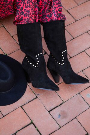 Botas de serraje en color negro. Acabado en punta. Detalle de tachuelas en la parte media de la bota. Caña caída. Altura tacón: 10 cm, suela 0,5 cm. Altura caña: 30 cm. 100% piel. Alabama Shop