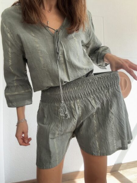 Conjunto de dos piezas en tono verde oliva, formado por blusa fluida con escote en pico y lazada con borlas, y short de cintura elástica. Ligero, fresco y con un aire boho muy especial, es perfecto tanto para el día a día como para planes más arreglados. <strong>Talla:</strong> única (equivale de la 36 a la 42) <strong>Composición:</strong> 100% algodón Alabama Shop