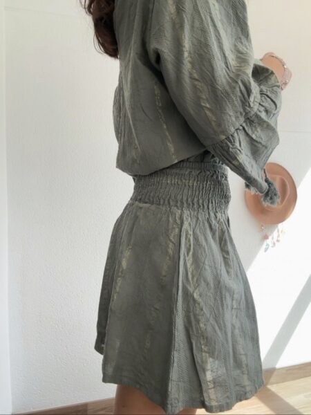 Conjunto de dos piezas en tono verde oliva, formado por blusa fluida con escote en pico y lazada con borlas, y short de cintura elástica. Ligero, fresco y con un aire boho muy especial, es perfecto tanto para el día a día como para planes más arreglados. <strong>Talla:</strong> única (equivale de la 36 a la 42) <strong>Composición:</strong> 100% algodón Alabama Shop