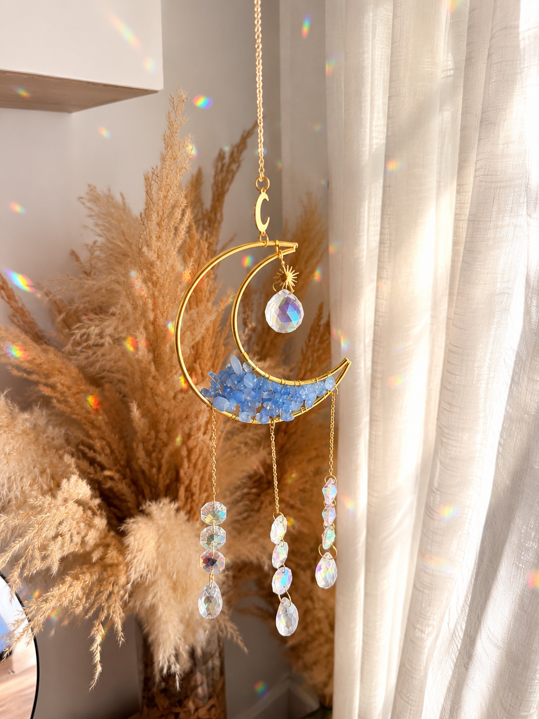 17c78ab3-fe1a-4689-b902-010d284e3ce5 Luz de Hadas: Luna de Angelita ✨
Un atrapasol mágico pensado para llenar cualquier rincón de luz y reflejos arcoíris. Su luna dorada está decorada con pequeñas piedras de angelita azul y cristales facetados que crean destellos preciosos con la luz del sol. Una pieza delicada y especial para aportar un toque boho, cálido y lleno de energía bonita a tu hogar. Alabama Shop