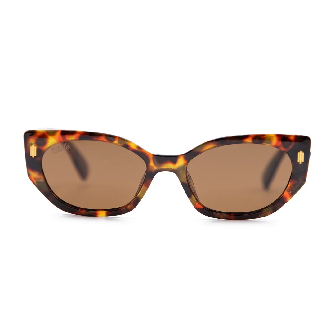 imagen-203 <strong>Esencia retro, carácter moderno y protección total.</strong> El modelo <strong>Fly Rosee</strong> destaca por su carismática silueta geométrica de estilo cat-eye y un atemporal estampado carey en tonos marrones y miel. Equipadas con <strong>lentes polarizadas, protección UV400 y categoría 3</strong>, estas gafas combinan unos cristales marrones de alta nitidez con sutiles detalles dorados en el frontal. El accesorio perfecto para aportar fuerza, personalidad y un aire vintage irresistible a cualquier look diario mientras cuidas al máximo tu mirada. Alabama Shop
