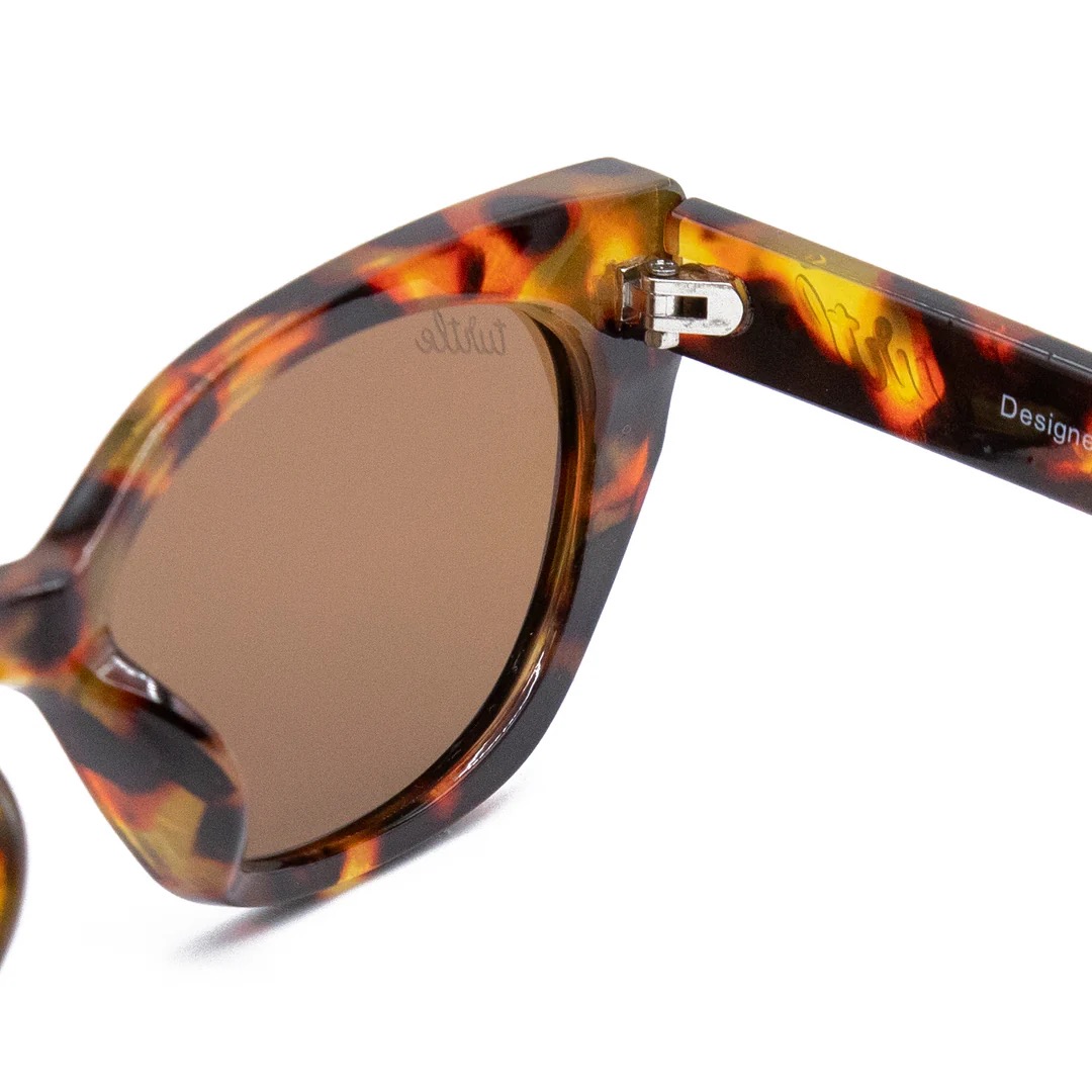 imagen-205 <strong>Esencia retro, carácter moderno y protección total.</strong> El modelo <strong>Fly Rosee</strong> destaca por su carismática silueta geométrica de estilo cat-eye y un atemporal estampado carey en tonos marrones y miel. Equipadas con <strong>lentes polarizadas, protección UV400 y categoría 3</strong>, estas gafas combinan unos cristales marrones de alta nitidez con sutiles detalles dorados en el frontal. El accesorio perfecto para aportar fuerza, personalidad y un aire vintage irresistible a cualquier look diario mientras cuidas al máximo tu mirada. Alabama Shop