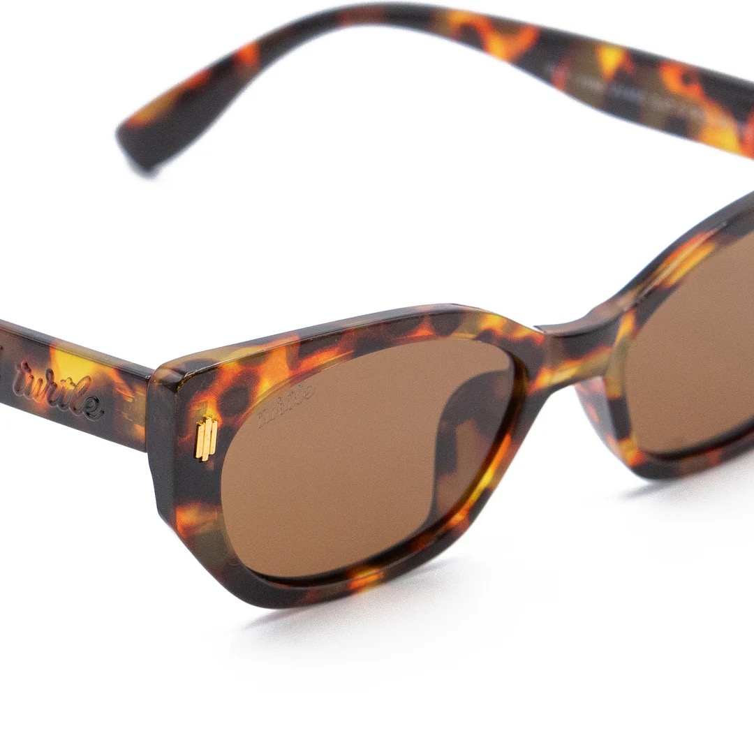 imagen-206 <strong>Esencia retro, carácter moderno y protección total.</strong> El modelo <strong>Fly Rosee</strong> destaca por su carismática silueta geométrica de estilo cat-eye y un atemporal estampado carey en tonos marrones y miel. Equipadas con <strong>lentes polarizadas, protección UV400 y categoría 3</strong>, estas gafas combinan unos cristales marrones de alta nitidez con sutiles detalles dorados en el frontal. El accesorio perfecto para aportar fuerza, personalidad y un aire vintage irresistible a cualquier look diario mientras cuidas al máximo tu mirada. Alabama Shop