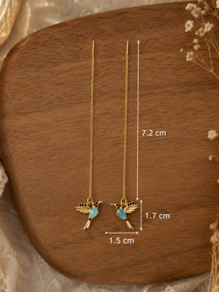 Pendientes colibrí de estilo delicado y femenino con acabado dorado y detalle azul turquesa. Su diseño ligero y elegante aporta un toque boho chic perfecto para elevar cualquier look, desde el más casual hasta uno más especial. Gracias a su cadena larga y fina estilizan muchísimo y quedan preciosos puestos. Medidas: Largo total: 7,2 cm Colibrí: 1,7 cm x 1,5 cm Alabama Shop