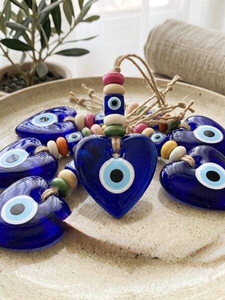 <strong>Protege tu paz y eleva la vibración de tu hogar.</strong> Este amuleto alquímico de 17 cm no es solo una pieza decorativa; es un centinela espiritual diseñado para neutralizar envidias y disolver energías densas. Forjado en vidrio azul cobalto con forma de corazón, actúa como un portal de luz que filtra quien entra en tu espacio sagrado. • <strong>Poder:</strong> Actúa como un escudo invisible contra el "mal de ojo". • <strong>Ubicación:</strong> Ideal para la entrada principal, donde vigila y purifica cada intención. • <strong>Esencia:</strong> Madera natural y vidrio soplado para un equilibrio perfecto entre tierra y espíritu. <strong>Siente la calma de saber que tu energía está a salvo.</strong> Alabama Shop