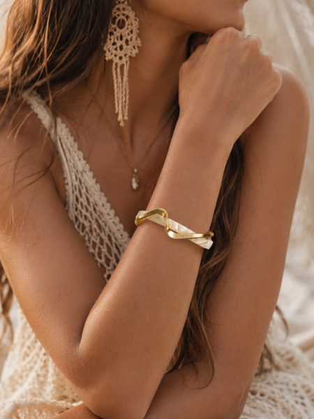 PULSERA NACAR OLA 3 <strong>Pulsera rígida abierta</strong> con diseño ondulado que combina el brillo del metal dorado con un elegante detalle efecto nácar en tono marfil. Una pieza original y sofisticada que aporta un toque especial a cualquier look, desde los más casuales hasta los más arreglados. Su diseño abierto permite adaptarse cómodamente a la muñeca, mientras que la combinación de acabados dorados y nacarados crea un contraste elegante y muy favorecedor. <ul> <li>Diseño rígido abierto</li> <li>Acabado dorado brillante</li> <li>Detalle efecto nácar en tono marfil</li> <li>Ligera y cómoda de llevar</li> <li>Ideal para elevar cualquier look</li> <li>Medidas aproximadas: 7 cm x 5 cm</li> <li>Apertura: 3,2 cm</li> </ul> Alabama Shop