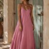 Vestido largo negro de inspiración boho confeccionado en un tejido fluido con una caída espectacular. Su escote drapeado y los finos tirantes que se cruzan en la espalda crean una silueta elegante y muy femenina, mientras que el corte al bies se adapta suavemente al cuerpo sin marcar. Un diseño minimalista, atemporal y versátil, perfecto para llevar con sandalias planas durante el día o elevar con joyas doradas y tacón en las noches de verano. Talla única: 36/40 Alabama Shop